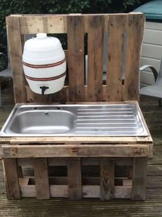 an outdoor sink made out of wooden pallets with a white jug on the back