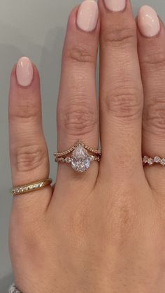 a woman's hand with three different rings on her fingers and one ring in the middle