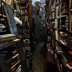 a narrow room filled with lots of books and stacks of books on the shelves in front of them