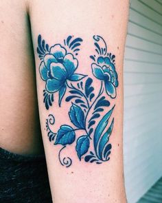 a woman's arm with blue flowers and leaves on the left side of her body