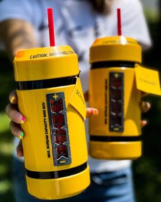 two people holding yellow cups with red straws in their hands and one is holding a cell phone