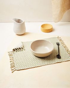 a bowl, fork and spoon on a placemat