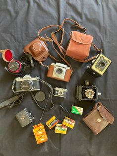 an assortment of old cameras and other items laid out on a bed