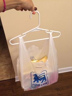 a person holding a plastic bag with food in it and hanging from a hook on the wall