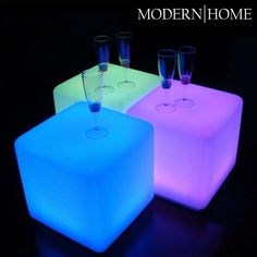 three different colored light up stools with glasses on them