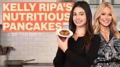 two women standing in front of a sign holding food