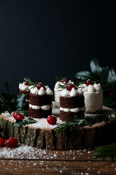 three small cakes with white frosting and cranberry toppings on a wood slice