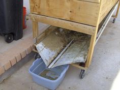 a wooden box sitting on top of a cart next to a blue bin filled with dirt