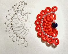 an orange beaded brooch sitting next to a drawing