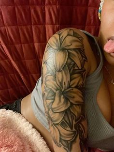 a woman laying on top of a bed with her tongue out and tattoos on her arm