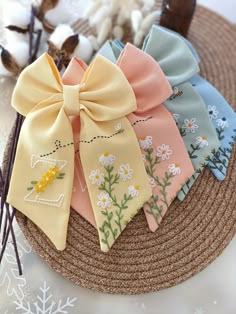 four different colored bows are on top of a straw hat with cotton flakes in the background