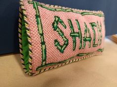 a pink and green pillow sitting on top of a wooden table next to a blue wall