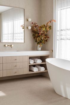 a bath room with a large mirror and a white tub in front of a window