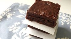 two pieces of brownie sitting on top of each other in front of a blue and white napkin