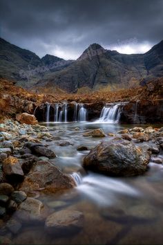 a small waterfall in the middle of a rocky mountain range with rocks and water running through it