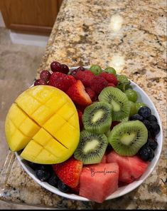 a white bowl filled with fruit on top of a counter