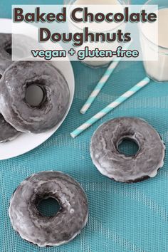 three glazed chocolate doughnuts sitting on top of a plate next to a glass of milk