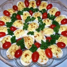 a platter full of deviled eggs with tomatoes and parsley