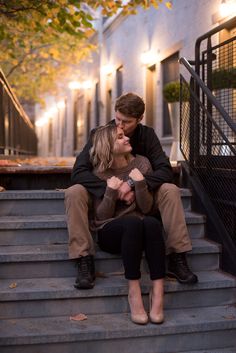 a man and woman are sitting on the steps outside an apartment building with their arms around each other