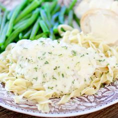 a plate with pasta, green beans and bread on it