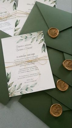 the wedding stationery is laid out on top of green envelopes with wax seals