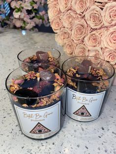 three cups filled with different types of chocolates and flowers on top of a table