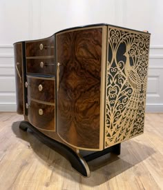 an ornate wooden cabinet with two drawers on one side and a peacock design on the other