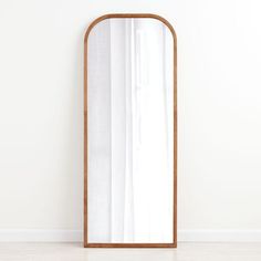 a large mirror sitting on top of a white floor next to a wooden framed wall