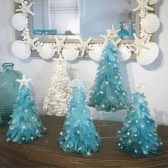 three blue and white christmas trees sitting on top of a table next to a mirror