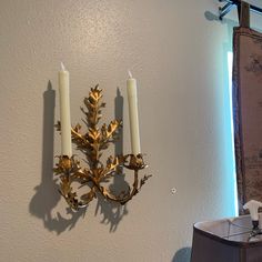 two candles are lit on the wall next to a candle holder with three candles in it