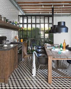 a kitchen with black and white checkered flooring next to a wooden dining table