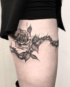 a woman's thigh with a rose and barbed wire tattoo on the side of her leg