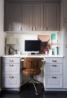 a desk with a computer on top of it in front of some drawers and cabinets