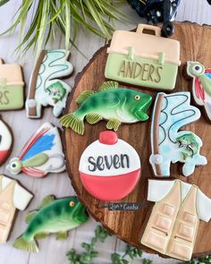 decorated cookies are displayed on a wooden platter with green plants and other decorative items