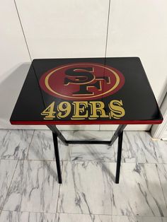 a side table with the san francisco sports team logo painted on it in black, red and gold