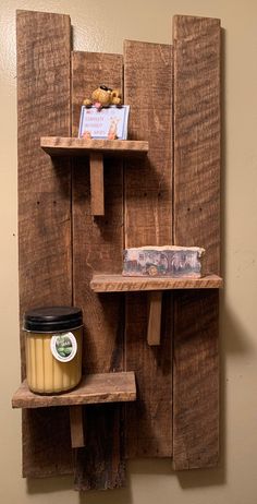 a wooden wall shelf with two shelves and a cup on top of it next to a jar of peanut butter