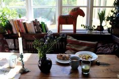 a wooden table topped with plates of food next to a vase filled with flowers and candles