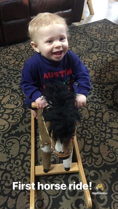 a toddler is sitting on a wooden toy horse