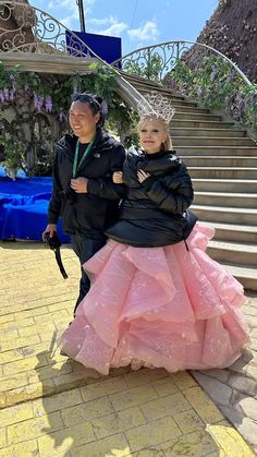 two people standing on the steps in front of some stairs with pink dresses and umbrellas