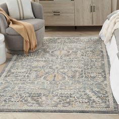 a large area rug with an ornate design on the floor in front of a bed