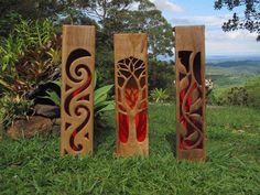 three wooden sculptures sitting on top of a lush green field