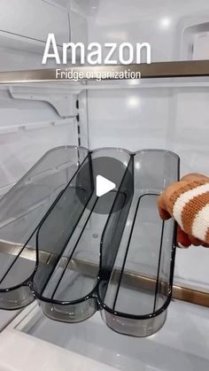 a person holding an item in their hand near some glass shelves on the refrigerator door