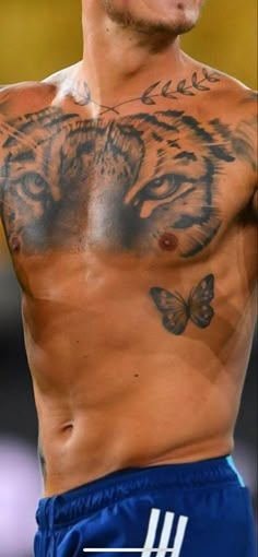 a man with a tiger tattoo on his chest is looking at the camera while wearing blue shorts