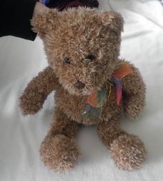 a brown teddy bear sitting on top of a bed