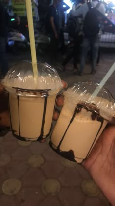 two drinks in plastic cups being held by someone's hand