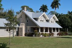 a large house with two story windows and white trim on the roof, surrounded by palm trees