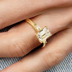 a woman's hand with a yellow gold ring and diamond engagement ring on it