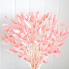 a vase filled with pink flowers sitting on top of a wooden table next to a white wall