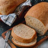 two loaves of bread sitting on top of a cutting board next to a knife