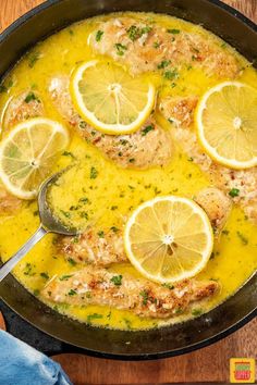 a pan filled with chicken and lemons on top of a wooden table